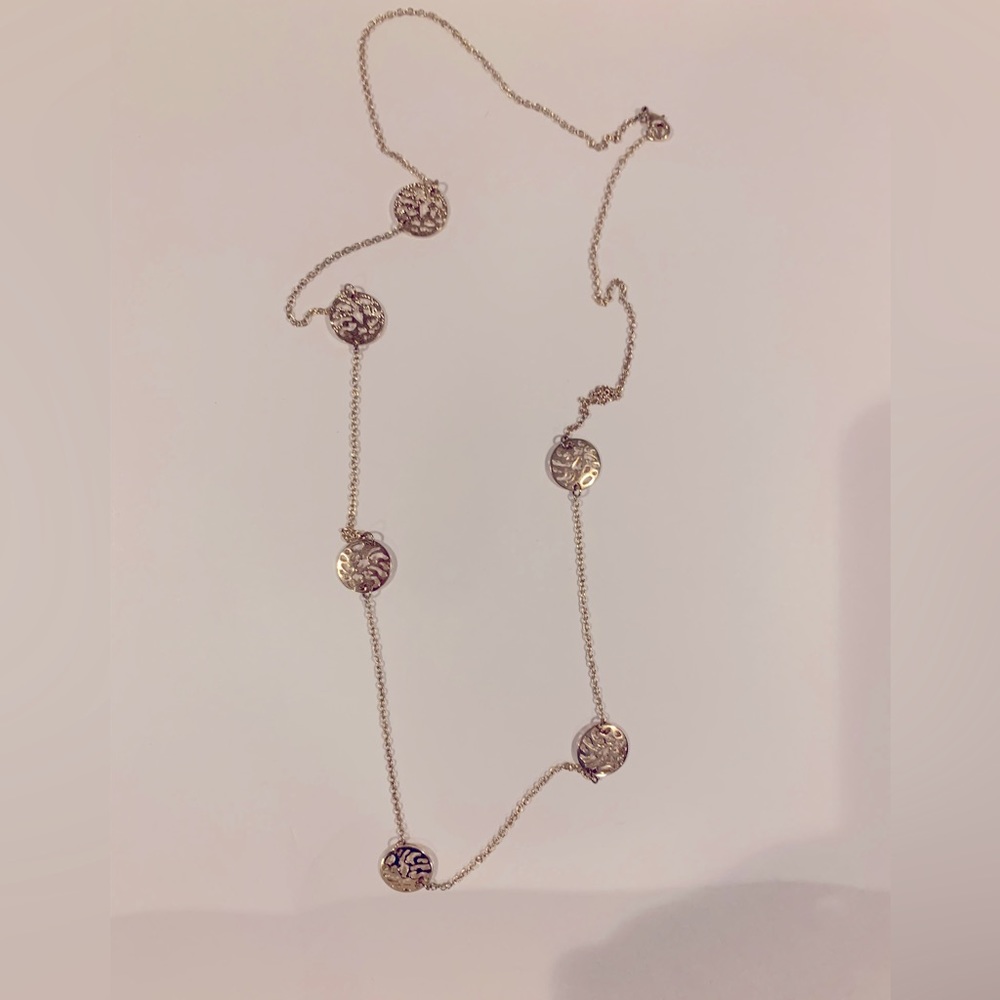 Gold color necklace with disc that has a pretty pattern on it
